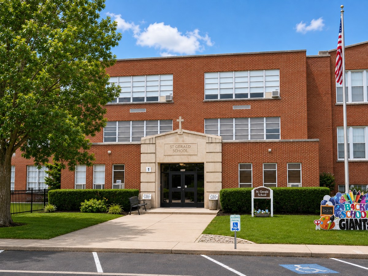The entrance to St. Gerald School — a two-storey red brick building with a carved stone doorway reading ST GERALD SCHOOL, a cross above it, and the American flag flying alongside.